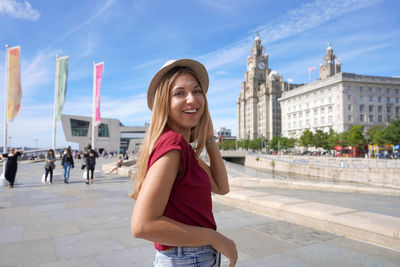 Smiling girl walking in pier head riverside in the city centre of liverpool, england