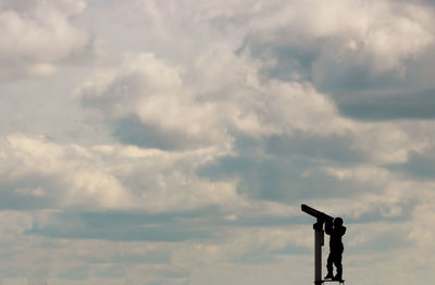 Low angle view of child looking at thé sky with binoculars