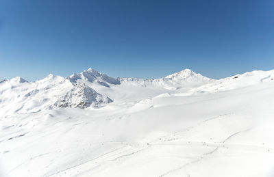 Scenic view of snowcapped mountains against clear blue sky