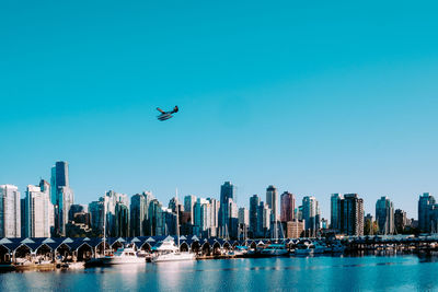 View of city at waterfront against blue sky