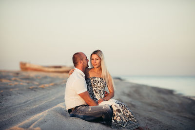 Happy young couple enjoying on a sandy beach at sunset.