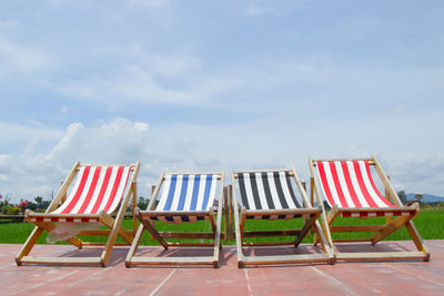 Empty chairs on beach against sky