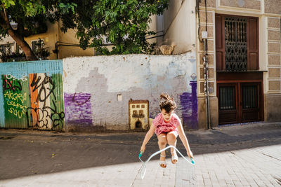 Young girl playing with a skipping rope in a colorful street