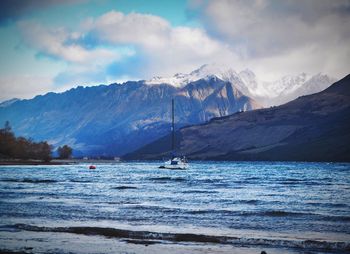 Scenic view of sea by snowcapped mountains against sky