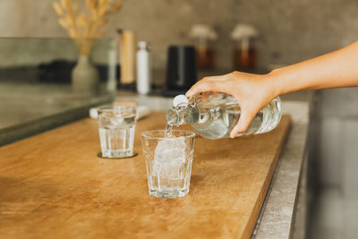 Hand pouring fresh purified water from a bottle into a glass.