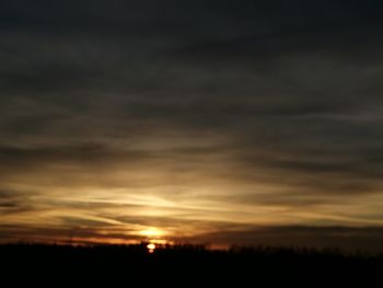 Silhouette landscape against dramatic sky during sunset