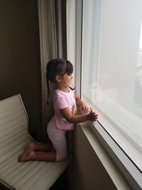 Girl sitting by window at home