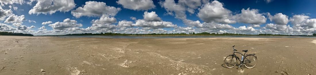 Panoramic view of person riding bicycle on beach