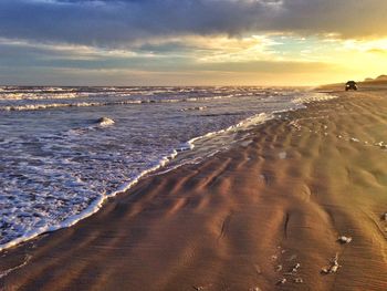 Scenic view of shore and sea against sky during sunset