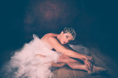 Semi-naked woman wearing tulle tutu against black background