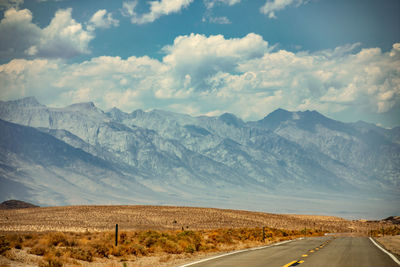 Road by mountains against sky