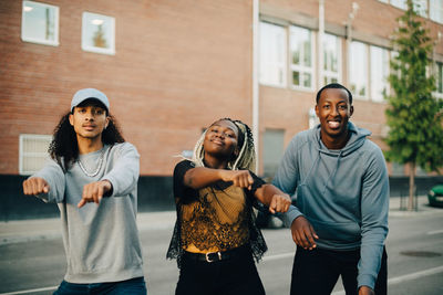 Portrait of teenage girl and men dancing on street in city