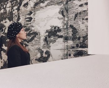 Side view of woman looking at snow covered window