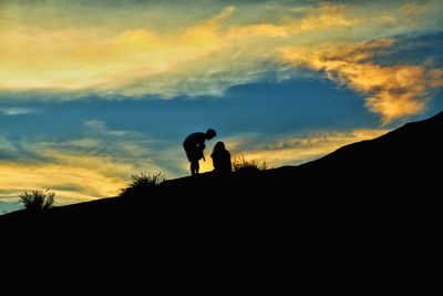 Silhouette men standing on mountain against sky during sunset