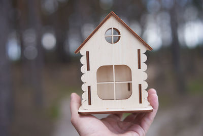 Close-up of hand holding small house against building