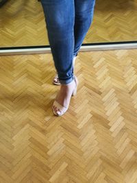 Low section of woman on hardwood floor at home