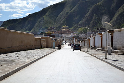 Road amidst mountains in city against sky