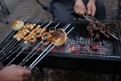 Friends preparing meat on barbecue grill