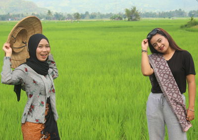 Portrait of smiling women standing on field against sky