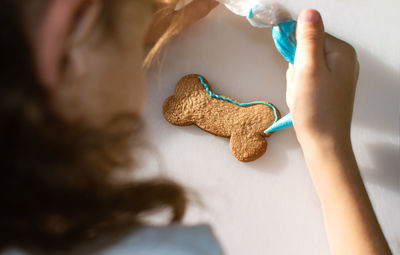 High angle view of girl icing cookie on table