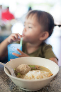 Soup bowl on table with girl having drink in background at restaurant