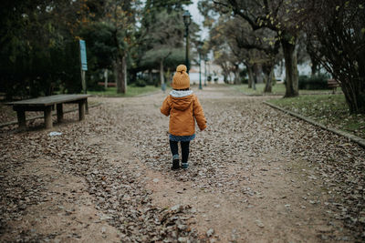 Rear view of woman walking on street during winter