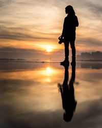 Silhouette person standing on shore during sunset