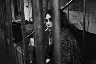 Young woman smoking cigarette seen through railing