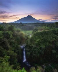 Scenic view of waterfall against sky during sunset