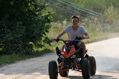 Portrait of teenage boy riding quadbike on dirt road