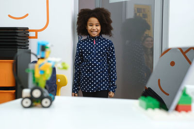 African american school girl entering modern class room door for science and constructing lesson