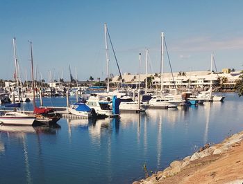 Sailboats moored in harbor against clear blue sky