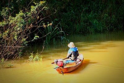 Rear view of man on boat in lake