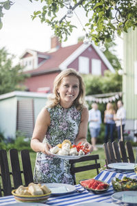 Portrait of a smiling woman against house and building