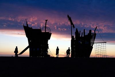 Silhouette people standing by sea against sky during sunset