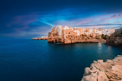 Buildings by sea against blue sky