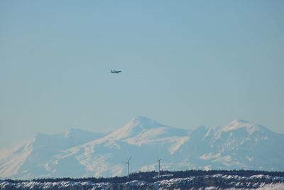 Airplane flying over mountains against clear sky