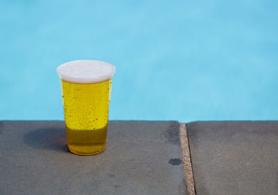 Close-up of drink on table by swimming pool