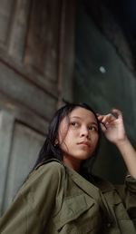 Portrait of young woman standing against wall