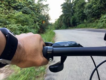 Cropped hand riding bicycle on road