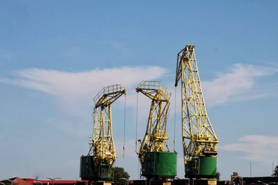 Low angle view of cranes against sky