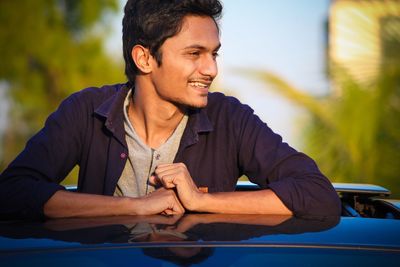 Young man looking away while standing in convertible car