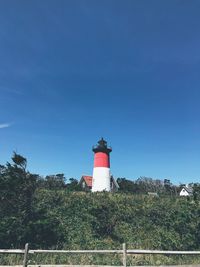 Low angle view of lighthouse by building against sky