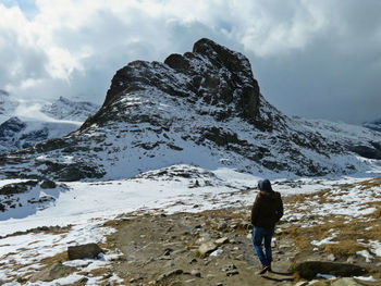 Rear view of person on snowcapped mountain against sky