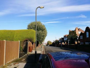 Road by trees against sky in city