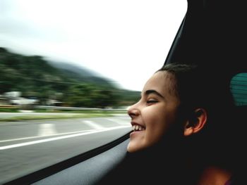 Smiling girl looking at window in car on road