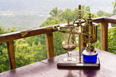 Close-up of coffee cup on table against trees