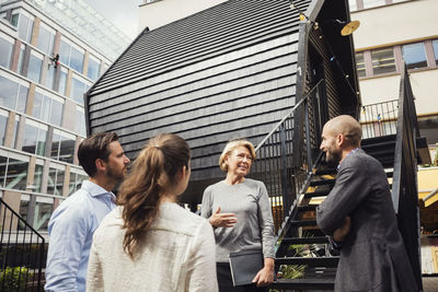 Business colleagues discussing outside log cabin at office yard