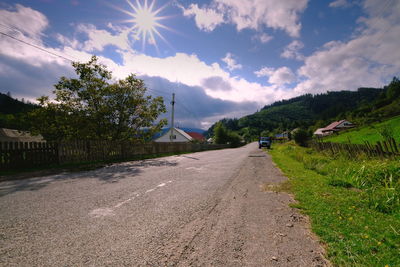 Road amidst trees and buildings against sky