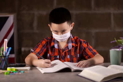 Portrait of boy studying while sitting on table